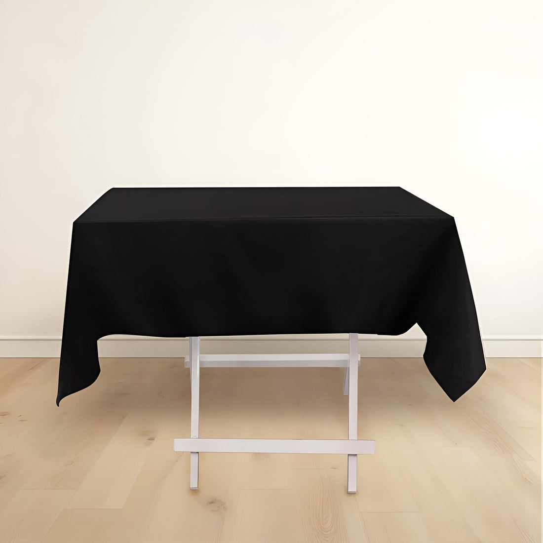 Black tablecloth draped over a white folding table in a minimalist setting.