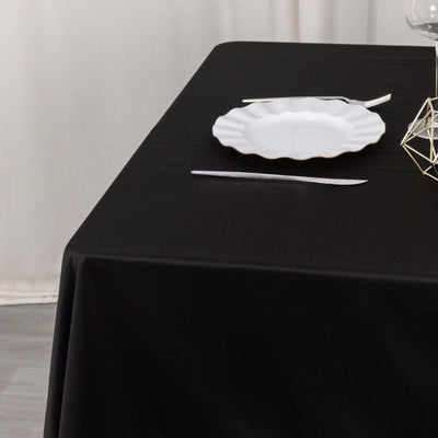 Black tablecloth with white plate and cutlery elegantly arranged.