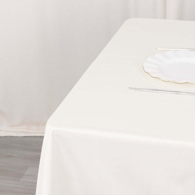 Elegant white tablecloth with polished silverware and a decorative plate.