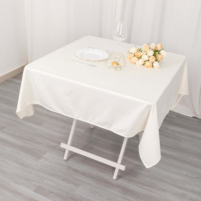 Elegant white tablecloth draped over a folding table with floral arrangement.