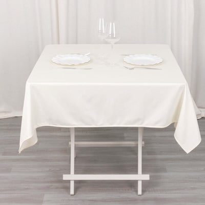 Cream tablecloth on a white table set with plates and glasses.