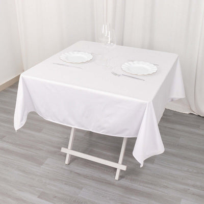 White table set with plates and glasses on a light wood floor.