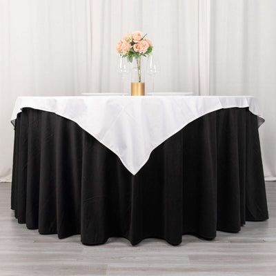 Round black table with white tablecloth, flowers, and glasses set elegantly.
