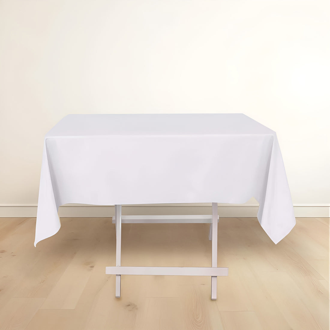 White tablecloth draped over a folding table on a light wooden floor.