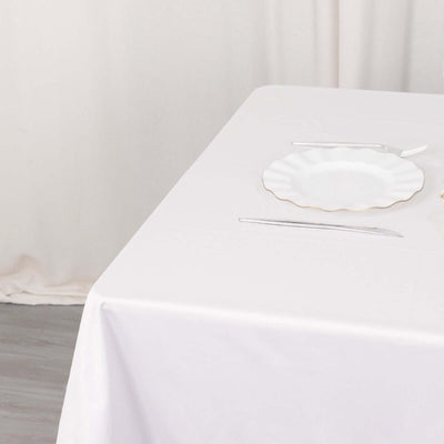 White table setting with a scalloped edge plate and silver utensils.