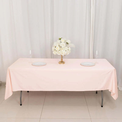 Elegant pink tablecloth with floral centerpiece and plates set for dining.