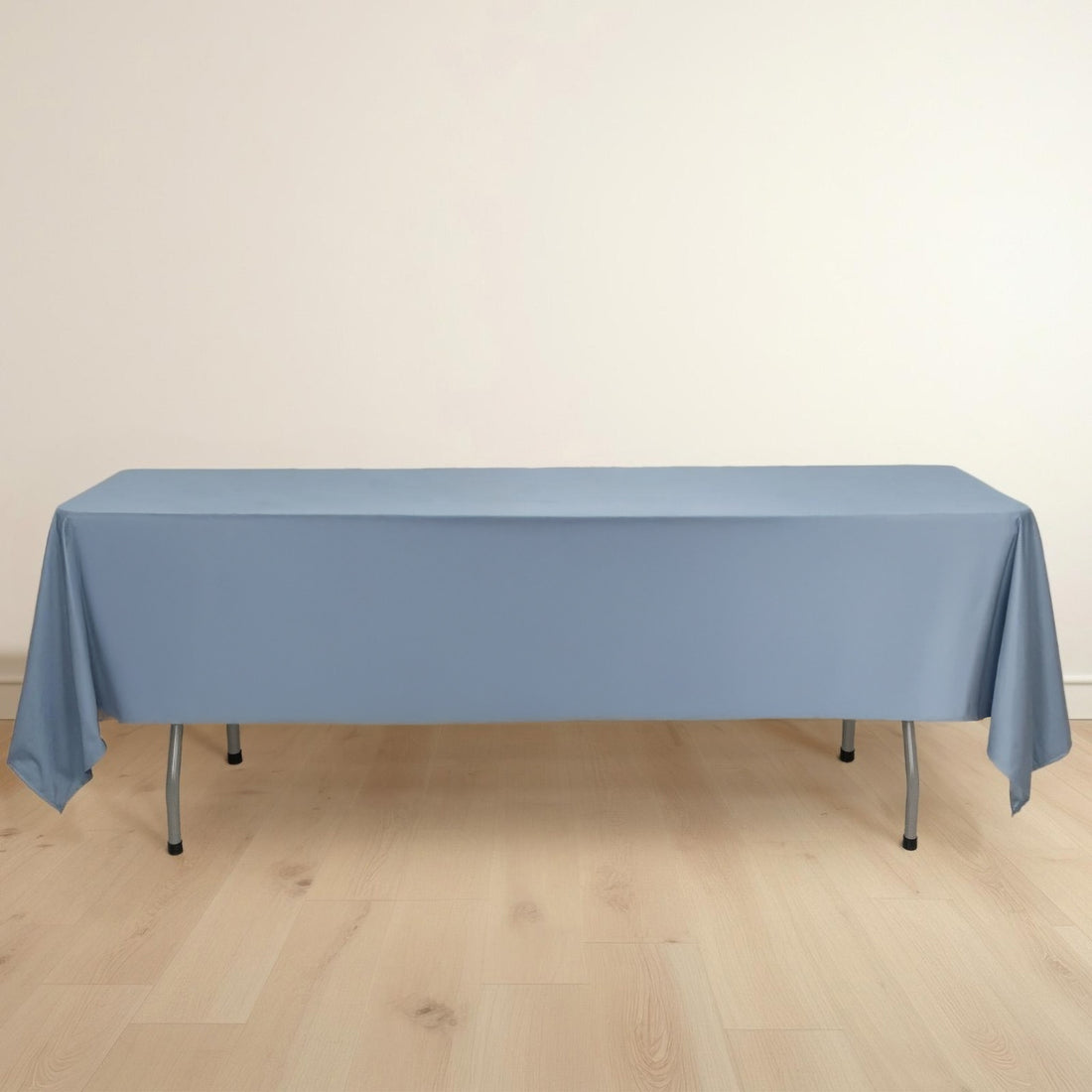 Blue tablecloth draped over a folding table on a light wooden floor.
