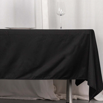 Black tablecloth draped over a table with a wine glass and plate on top.