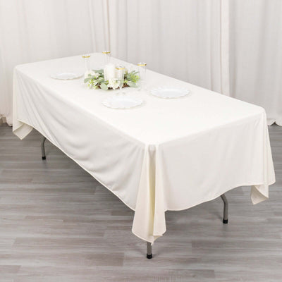 White tablecloth draped over a table, styled with candles and decorative plates.