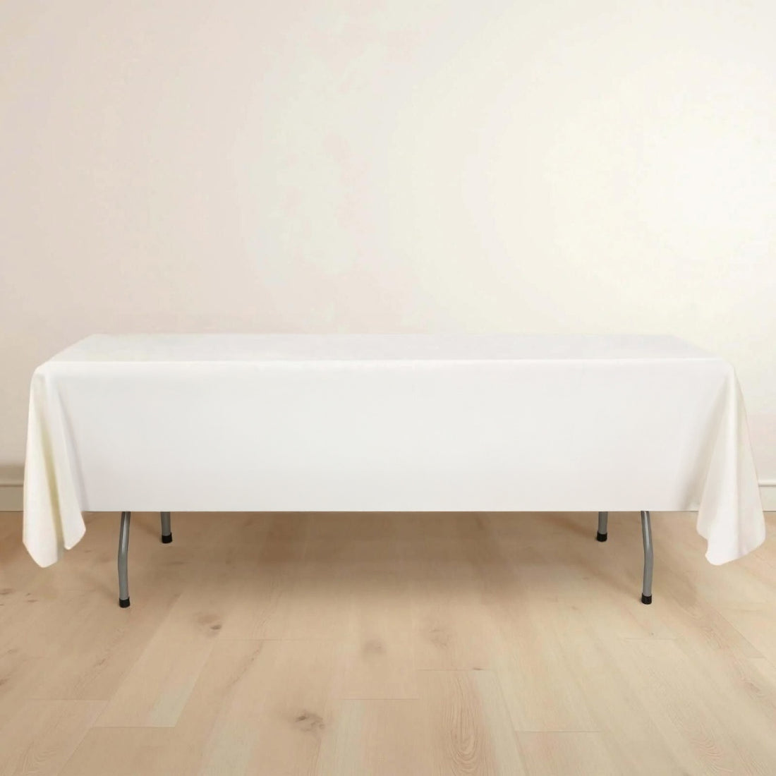 White table with a tablecloth on a light wooden floor.