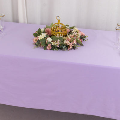 Gold birdcage centerpiece surrounded by flowers on a lilac tablecloth.