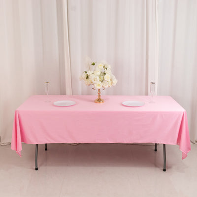 Pink tablecloth with floral centerpiece and plates, elegantly set for an event.
