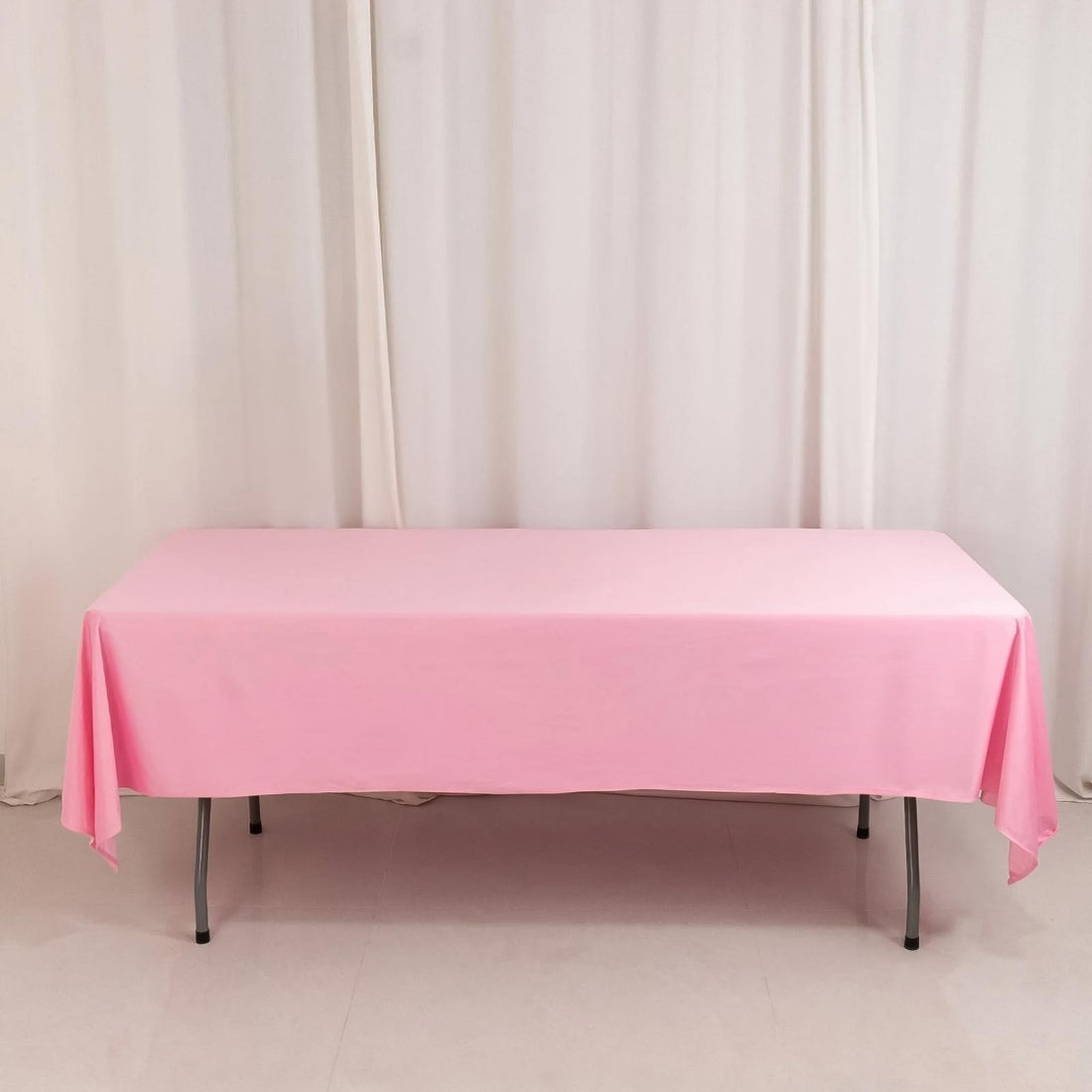 Pink tablecloth draped over a folding table in a studio setting.