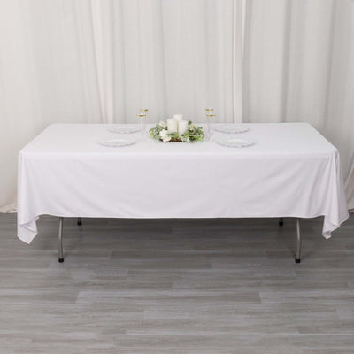 White tablecloth draped over a table, styled with plates and decorative elements.