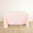 Pink tablecloth draped over a table on a light wooden floor.