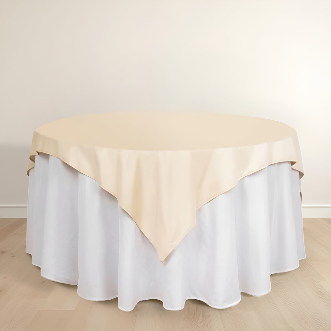 Round table with beige tablecloth and white skirt on a plain background.