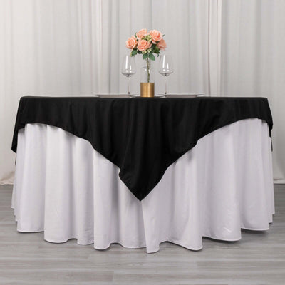 Elegant black and white tablecloth with flowers and glasses on a dining table.