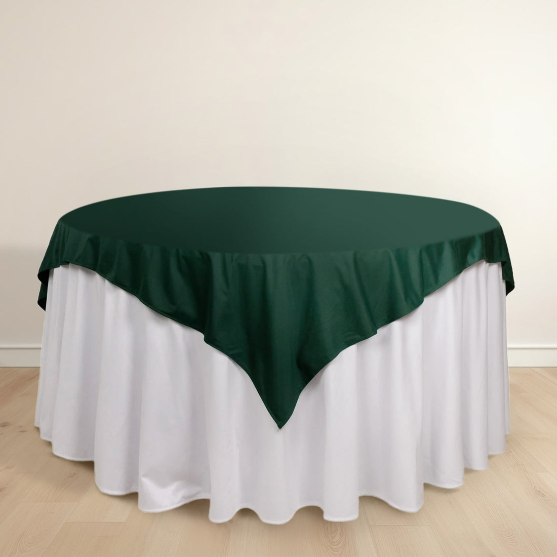 Green tablecloth draped over a round table with a white skirt.