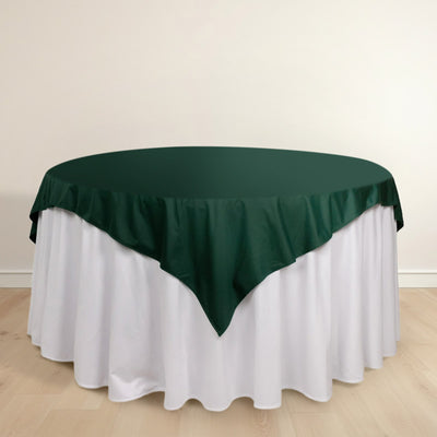 Green tablecloth draped over a round table with a white skirt.