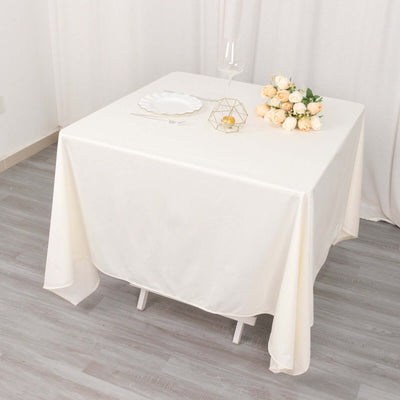 Elegant white tablecloth draped over a table with decor and flowers.