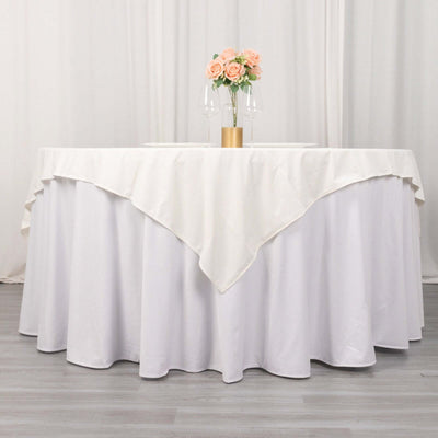 Elegant round table with white tablecloth, adorned with flowers and glassware.