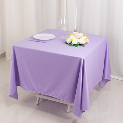Purple tablecloth draped over a table with floral centerpiece and dinnerware.