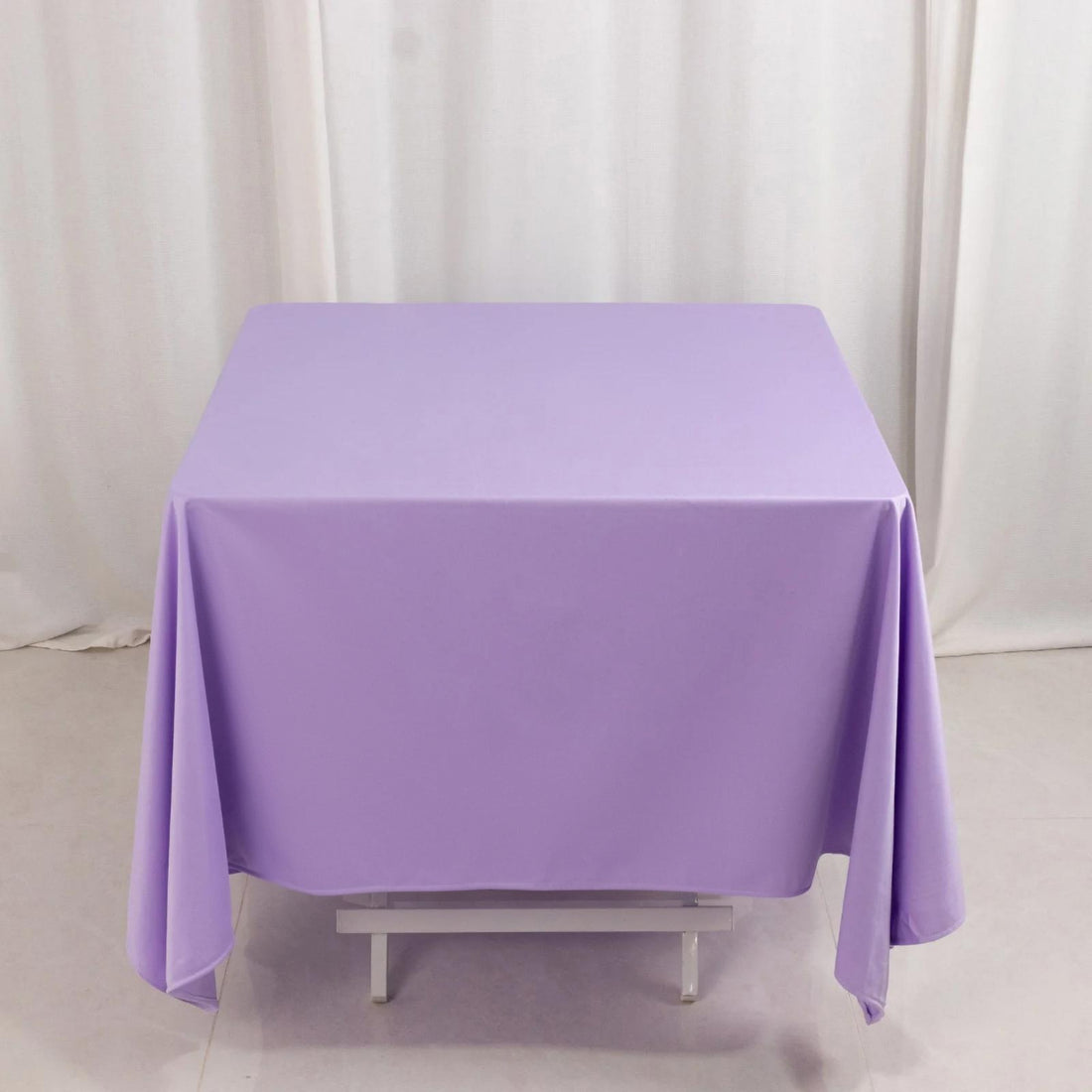 Purple tablecloth draped over a table on a plain backdrop.