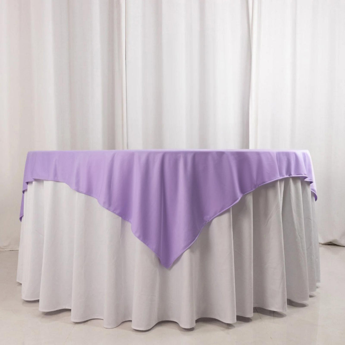 Purple tablecloth draped over a white table in a studio setting