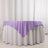 Purple tablecloth draped over a white table in a studio setting