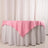 Pink tablecloth draped over a round table with white skirt.