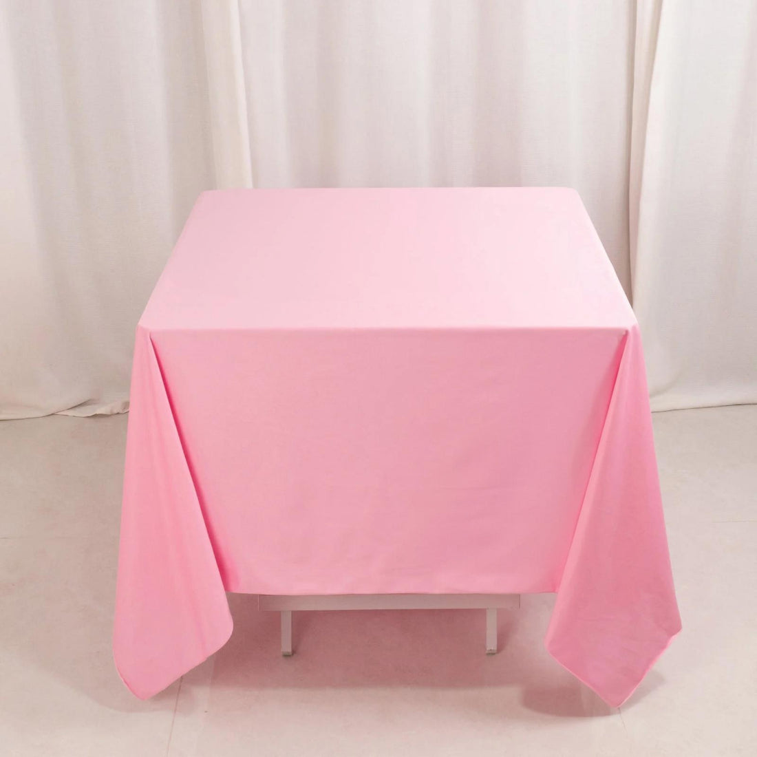 Pink tablecloth draped over a table against a neutral background.