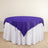 Purple tablecloth draped over a round table with a white skirt.