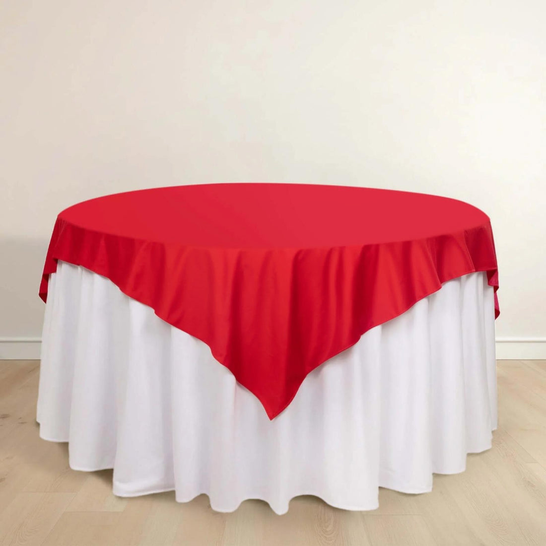 Red tablecloth draped elegantly over a round table with white skirt.