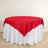 Red tablecloth draped elegantly over a round table with white skirt.