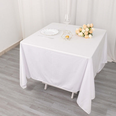 White table with elegant tablecloth, wine glass, and flower arrangement.