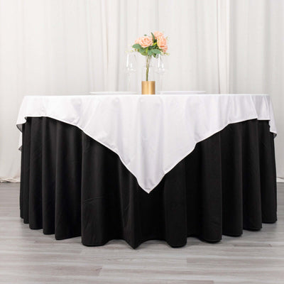 Elegant round table with black and white linen, centerpiece of flowers and glasses.