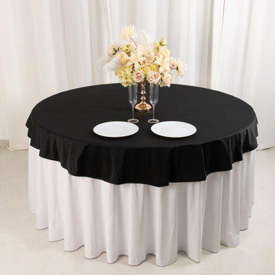 Elegant round table set with black and white tablecloth, adorned with floral centerpiece.