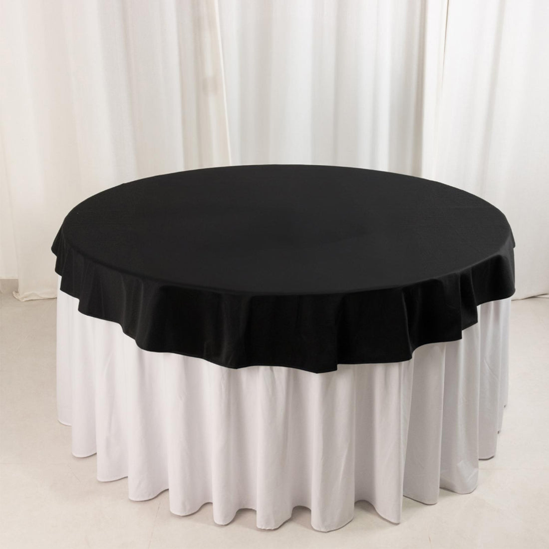Black round tablecloth with white skirt draping for elegant table settings.