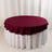 Burgundy tablecloth draped over a round table with a white skirt