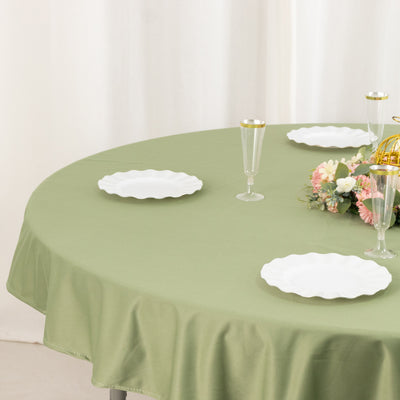 Round olive green tablecloth with white plates and floral centerpiece.