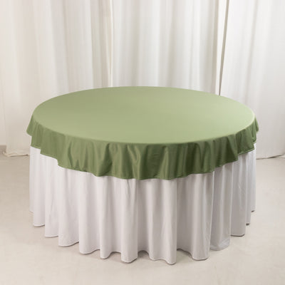 Green tablecloth on a round table with white skirt draping.