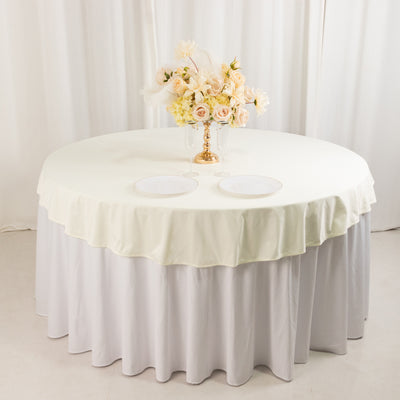 Round table with cream tablecloth, white skirt, and floral centerpiece.