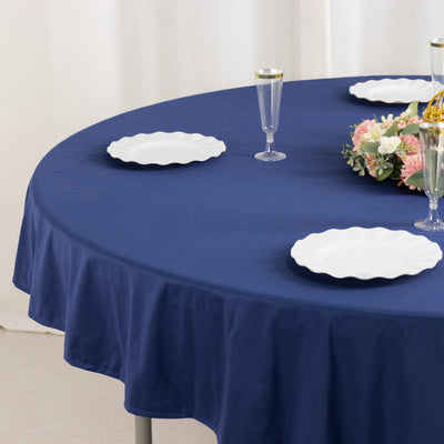 Navy blue tablecloth draped over a round table with white plates and floral centerpiece.