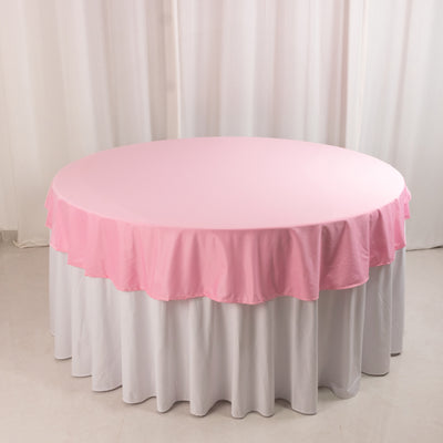 Round pink tablecloth draped over a white table.