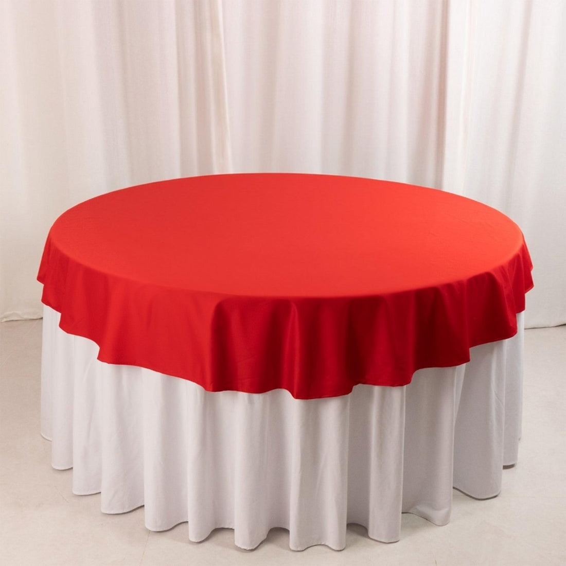 Red round tablecloth draped over a white table.