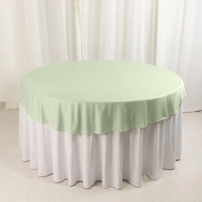 Round mint green table cover on a white tablecloth.