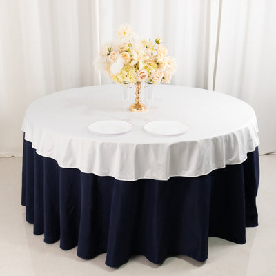 Round table with white and navy tablecloth, decorated with flowers and plates.