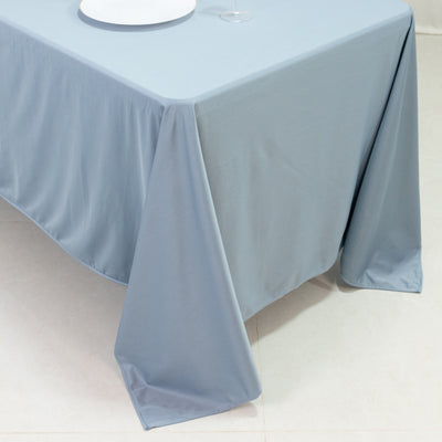 Light blue tablecloth draping over a table corner with a plate and glass.