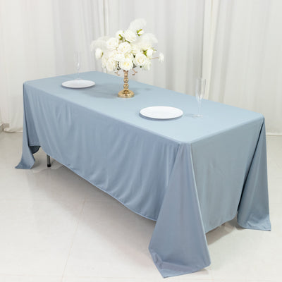 Elegant blue tablecloth with white plates and floral centerpiece in a staged setting.