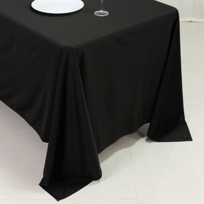 Black tablecloth draped over a table with a plate and glass on top.